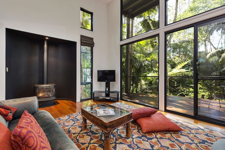 Living area with fireplace and access to the furnished balcony at Pethers Rainforest Retreat