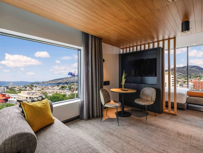 Movenpick Hobart's guest room with living area and picture window overlooking Hobart