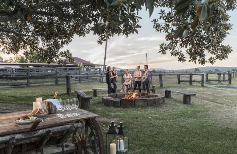 Friends gathered near an outdoor dining area and fire pit at Spicers Hidden Vale